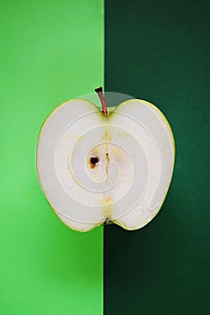 Half a ripe green apple on a green background