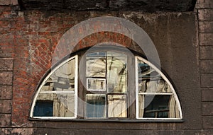 Half-round window an old crumbling brick wall