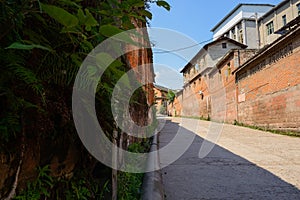 Half-shaded slopy road between old brick buildings in sunny summer afternoon