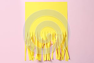 Half shredded sheet of yellow paper on pink background, top view