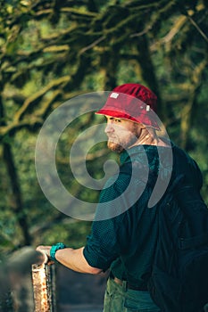 Hiker with backpack walking in mountain forest, climbing to the cliff