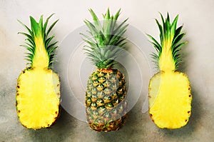 Half slice of fresh pineapple and whole fruit on gray background. Top View. Copy Space. Bright pineapples pattern for