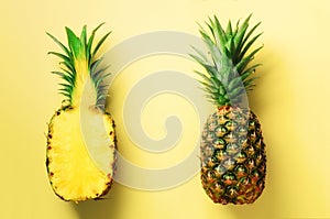 Half slice of fresh pineapple and whole fruit on yellow background. Top View. Copy Space. Bright pineapples pattern for