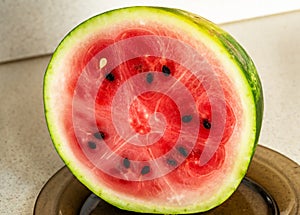 Half of sliced watermelon on brown plate on table