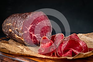 Half a smoked bresaola and cut pieces on a chopping Board. Italian Antipasti