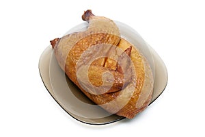 Half smoked chicken carcass on a plate on white background