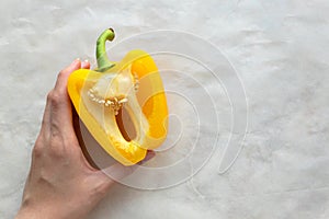 Half of sweet yellow pepper in female hand on light background photo