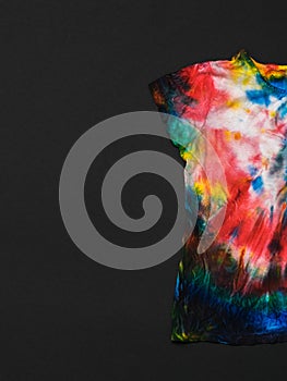 Half t-shirt in tie dye style on a black background. Flat lay.