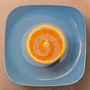 A half tangerine or a mandarin on a blue plate. Closeup and texture with the pulps an orange