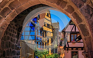 Half timbered houses through a stone arch, Alsatian Wine Route, Riquewihr France