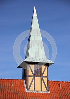 Half-timbering tower with verdigris roof on red tile building