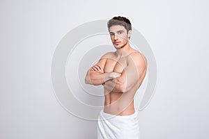 Half-turned portrait of naked handsome sexual attractive brunette guy with muscular body white towel on hips standing with