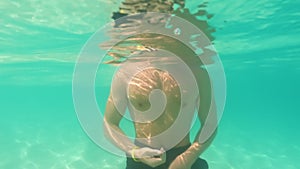 Half underwater, clear turquoise ocean waves, close up video. Boy is going to swim in sea. Thailand, Bamboo Island - excellent