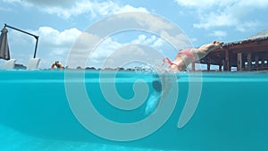 HALF UNDERWATER: Playful young female traveler jumps head first into empty pool. photo