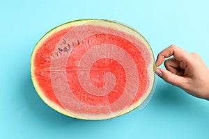 Half watermelon fruit with hand on color background photo