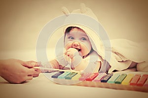 Half year baby girl playing with xylophone toy on blanket