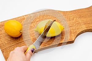Fresh lemons a cutting board.A half of a yellow lemon on a wooden chopping board with a knife.Composition of delicious