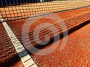 Halfcourt tennis clay court view with net, white lines and shadows photo