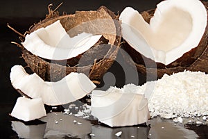 Halfs of coconut, pieces of coconat, coconut flakes on black background.