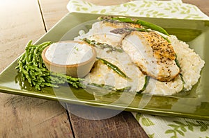 Halibut with asparagus risotto on green plate