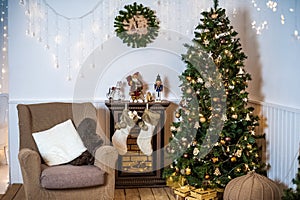 living room decorated for Christmas or New Year. Armchair with knitted plaid, pouf, fireplace, tree, beautiful interior in a