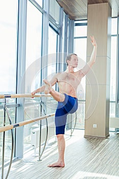 In the hall man doing stretching near Barre