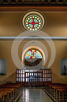 Hall with wooden benches and a round stained-glass window above the entrance