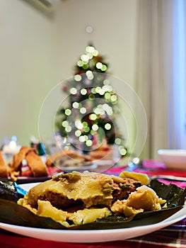 Hallaca served with jam bread with christmas tree at the background. Hallaca is a typical Venezuelan food served during holidays photo