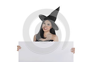 Halloween asian witch with hat holding blank white board