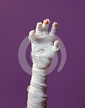 Halloween background. A bandaged hand of a zombie on a purple background. Halloween design