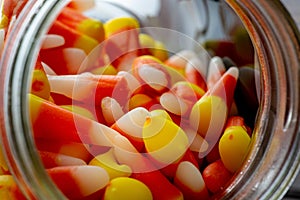 Halloween background frame consisting of a jar full of candy corn on a dark wooden table with a black table that you can personali