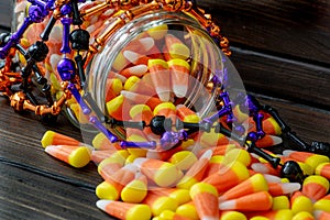 Halloween background frame consisting of a jar full of candy corn on a dark wooden table with a black table that you can personali