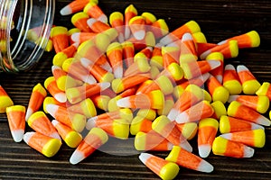 Halloween background frame consisting of a jar full of candy corn on a dark wooden table with a black table that you can personali