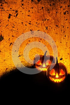 Halloween background wallpaper with jack o lantern scary pumpkins on grunge textured orange backdrop