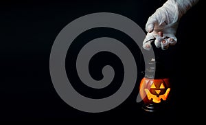 Halloween background. Zombie hand holding a lantern in the form of a pumpkin on a dark background. Halloween design. Copy space