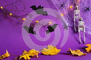 Halloween backgrounds of Jack lantern pumpkin glowing garland, spider web, skeleton on a rope, spiders and black bats on a purple