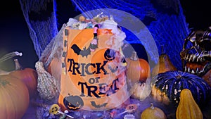 Halloween bag full of candies and sweets. Trick or treat, Halloween spooky scenery with pumpkins, misty fog, candies, skull