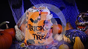 Halloween bag full of candies and sweets. Trick or treat, Halloween spooky scenery with pumpkins, misty fog, candies and spiders