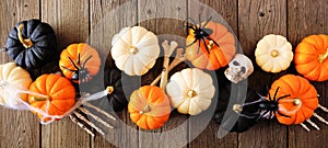 Halloween banner with orange, black and white pumpkins, bones and spiders against rustic wood