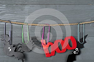 Halloween bats, spider and red `boo` photo booth props hanging on a twine with large colorful paper clips.