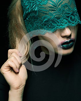 Halloween beauty portrait of young beautiful woman with green lacy ribbon on eyes on black