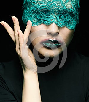 Halloween beauty portrait of young beautiful woman with green lacy ribbon on eyes on black