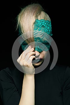 Halloween beauty portrait of young beautiful woman with green lacy ribbon on eyes on black