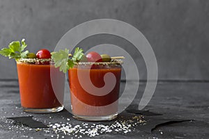 Halloween Bloody Mary cocktails served with pickled veggies tomatos, olive and celery and paper bats on a dark background