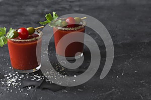 Halloween Bloody Mary cocktails served with pickled veggies tomatos, olive and celery and paper bats on a dark background