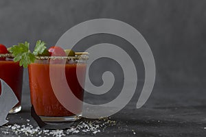 Halloween Bloody Mary cocktails served with pickled veggies tomatos, olive and celery and paper bats on a dark background