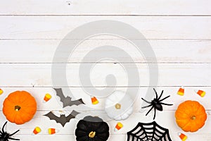 Halloween bottom border with black, orange and white decor and candy over white wood