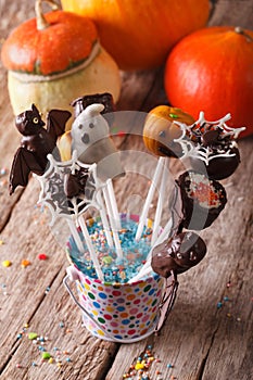 Halloween cake pop on the table and pumpkins. vertical