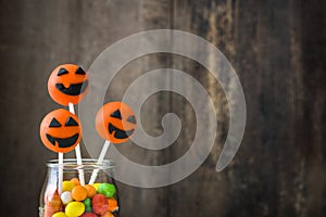 Halloween cake pops and colored candies on a rustic wooden background