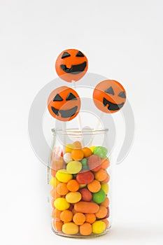 Halloween cake pops and colored candies on white background